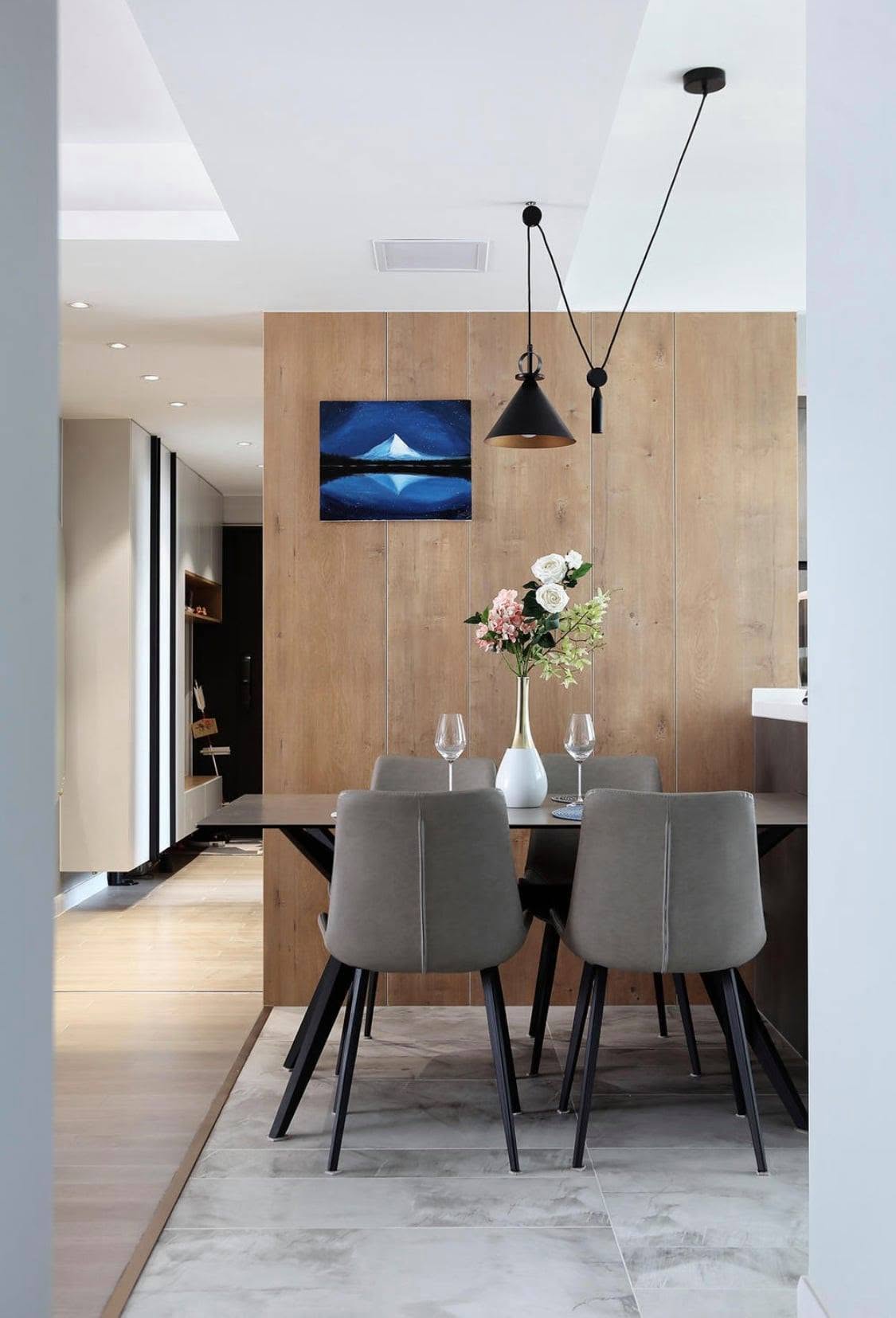 Dining nook framed by a full-height oak panel wall with a black pendant lamp