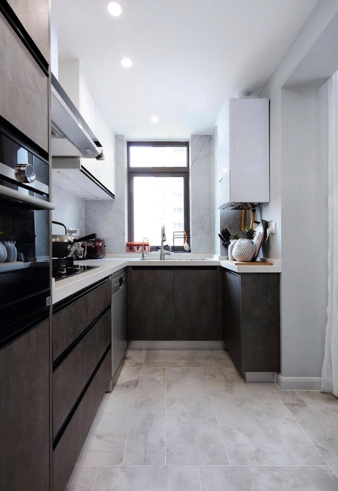 Galley kitchen with dark cabinetry, marble backsplash and stone flooring